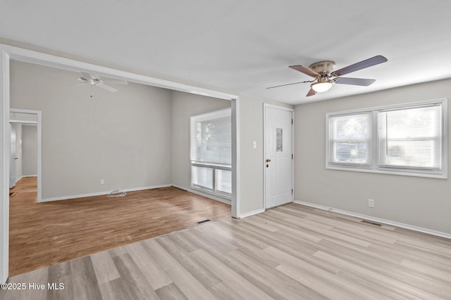 interior space featuring a ceiling fan, visible vents, light wood-style flooring, and baseboards