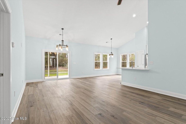 unfurnished living room with hardwood / wood-style floors, high vaulted ceiling, and a chandelier