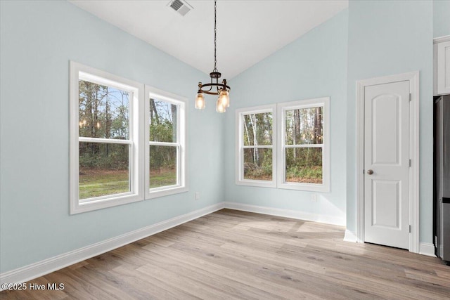 unfurnished dining area with lofted ceiling, a notable chandelier, and light wood-type flooring