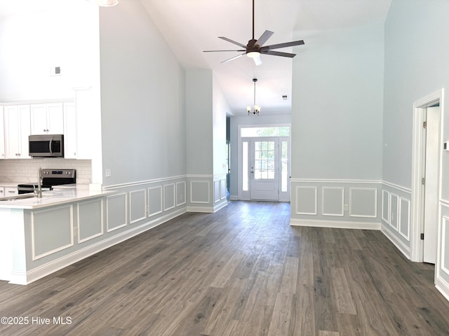 657 Boundary Loop NW, Carolina Shores, NC 28467 - unfurnished living room featuring high vaulted ceiling, a ceiling fan, dark wood-style floors, a decorative wall, and a wainscoted wall