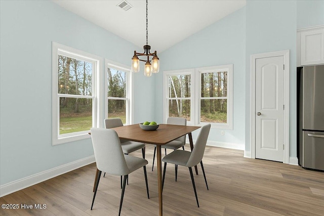 657 Boundary Loop NW, Carolina Shores, NC 28467 - dining area with a chandelier, baseboards, light wood-style flooring, and high vaulted ceiling