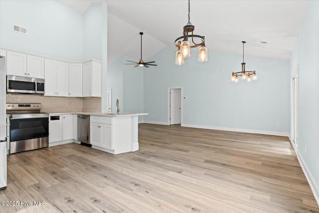 657 Boundary Loop NW, Carolina Shores, NC 28467 - kitchen with appliances with stainless steel finishes, a chandelier, high vaulted ceiling, a peninsula, and decorative backsplash