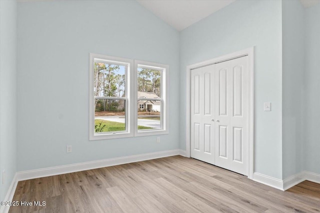 unfurnished bedroom with vaulted ceiling, light hardwood / wood-style floors, and a closet