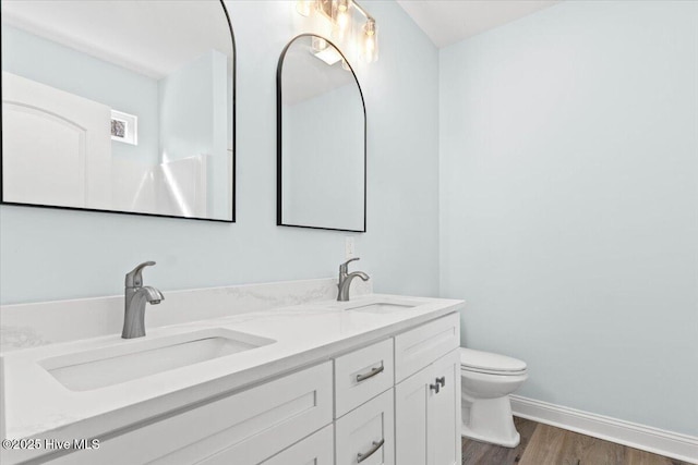 657 Boundary Loop NW, Carolina Shores, NC 28467 - bathroom featuring wood finished floors, toilet, double vanity, and baseboards