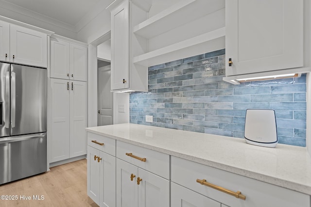 kitchen featuring stainless steel fridge with ice dispenser, white cabinetry, ornamental molding, and light stone counters