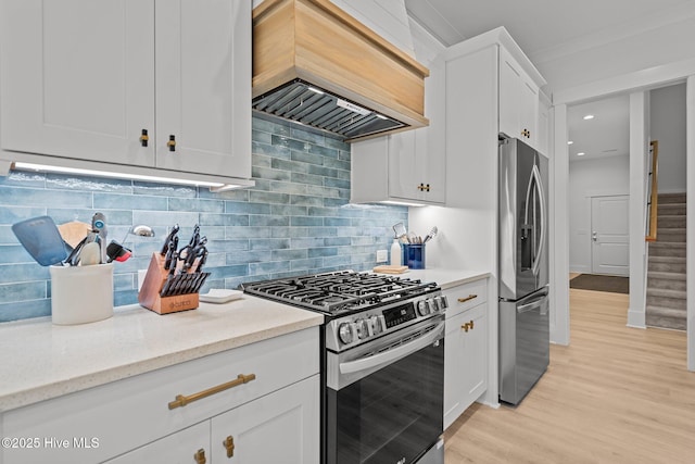 kitchen featuring white cabinets, appliances with stainless steel finishes, custom exhaust hood, backsplash, and light wood-type flooring