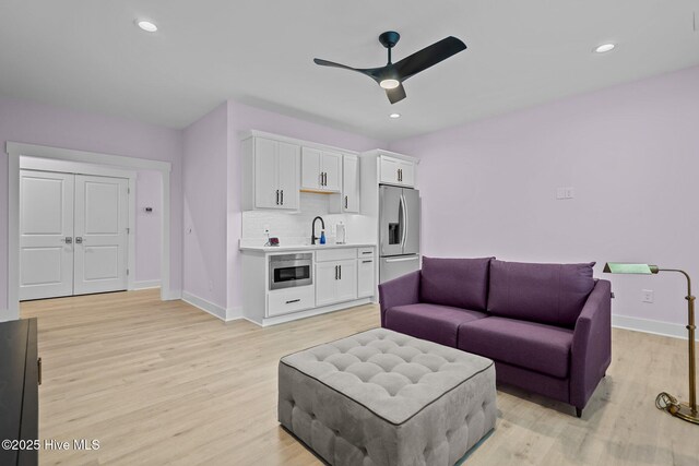 living room with ceiling fan, sink, and light hardwood / wood-style floors