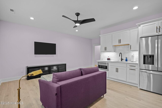 living room featuring ceiling fan, light hardwood / wood-style flooring, and sink