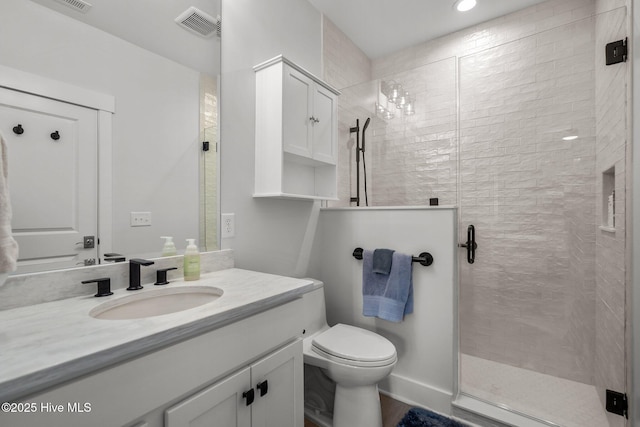 bathroom featuring a shower with shower door, toilet, and vanity