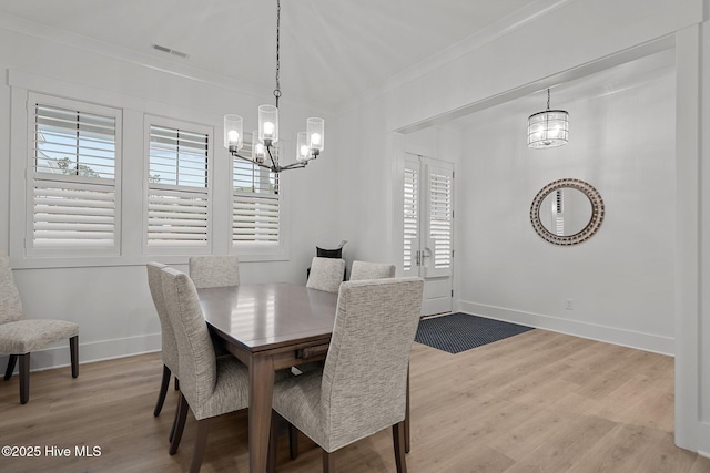 dining room with light wood-type flooring, an inviting chandelier, crown molding, and plenty of natural light