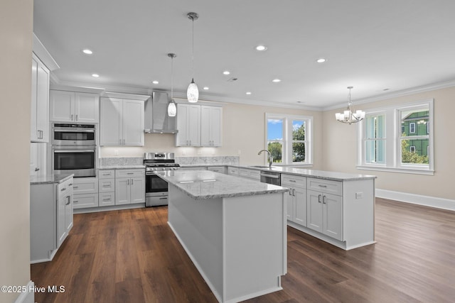 kitchen featuring appliances with stainless steel finishes, decorative light fixtures, wall chimney exhaust hood, white cabinets, and a center island