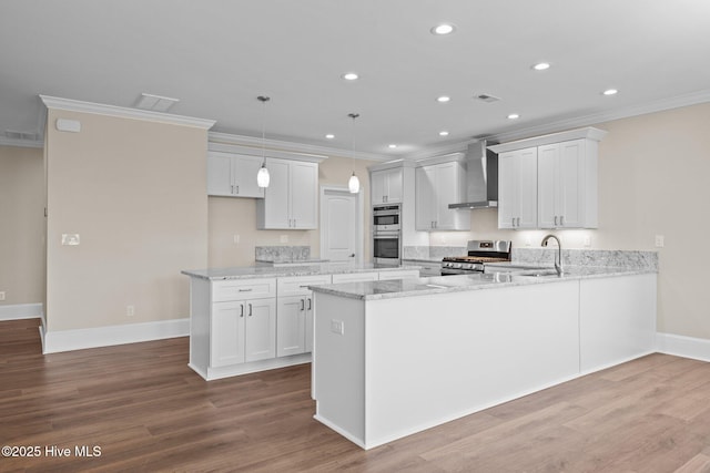 kitchen featuring pendant lighting, wall chimney exhaust hood, white cabinetry, stainless steel appliances, and sink