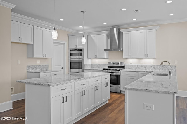 kitchen with stainless steel appliances, wall chimney range hood, pendant lighting, white cabinets, and sink