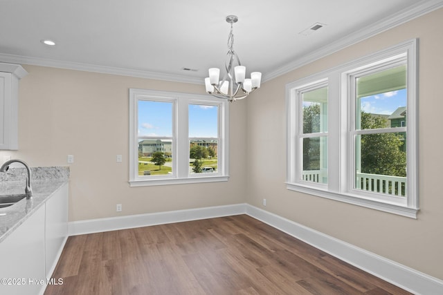 unfurnished dining area with a healthy amount of sunlight, sink, an inviting chandelier, and ornamental molding