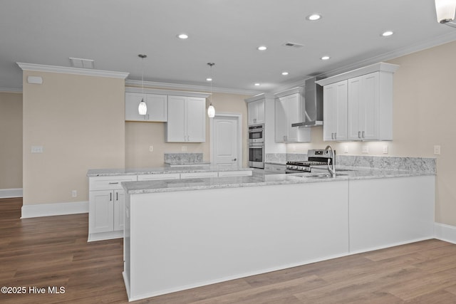 kitchen featuring white cabinets, appliances with stainless steel finishes, wall chimney exhaust hood, hardwood / wood-style flooring, and light stone counters