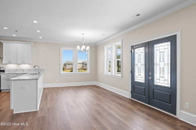 foyer entrance featuring an inviting chandelier, hardwood / wood-style floors, french doors, crown molding, and sink