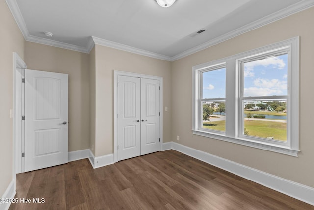 unfurnished bedroom featuring dark wood-type flooring, a closet, and crown molding