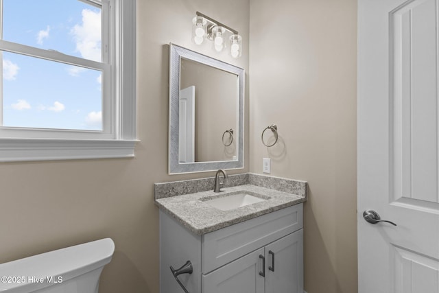 bathroom featuring a wealth of natural light, toilet, and vanity