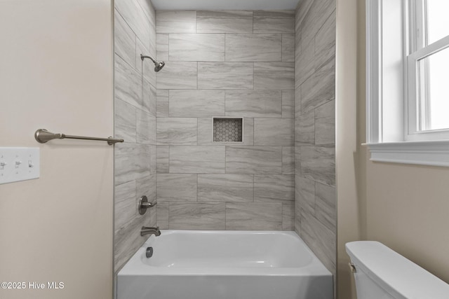 bathroom with toilet and tiled shower / bath combo