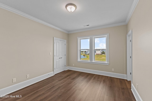 spare room featuring dark wood-type flooring and crown molding