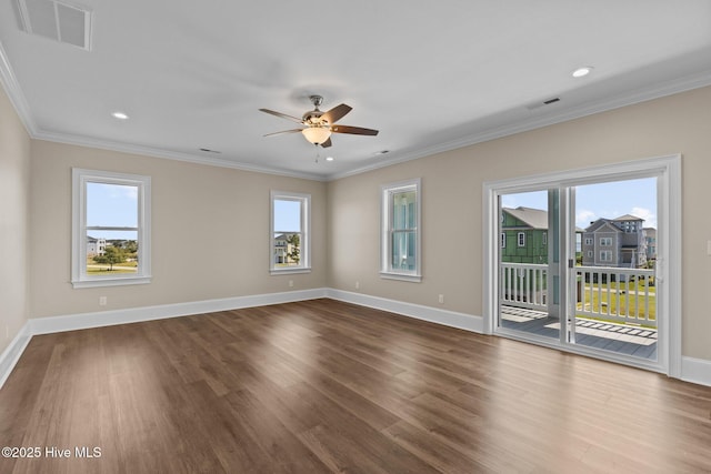 empty room featuring a healthy amount of sunlight, ornamental molding, and hardwood / wood-style floors