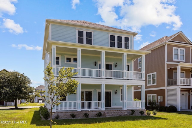 view of front facade with a balcony, a front lawn, and a porch