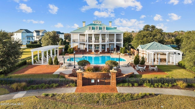 back of property featuring a pergola, a yard, a fenced in pool, a balcony, and a patio