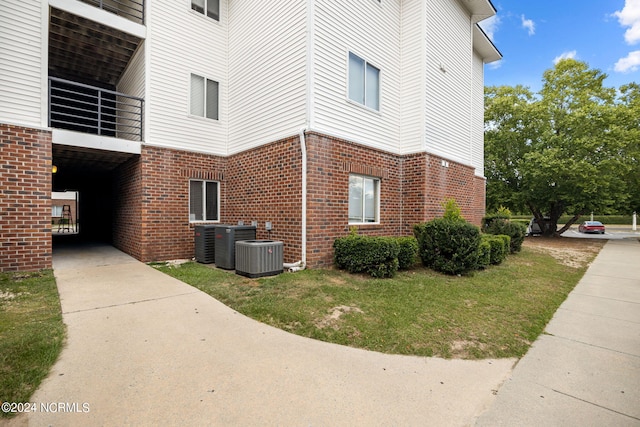 view of side of home featuring cooling unit and a yard