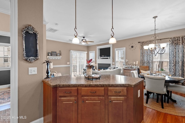 kitchen featuring pendant lighting, ceiling fan with notable chandelier, light hardwood / wood-style flooring, and ornamental molding