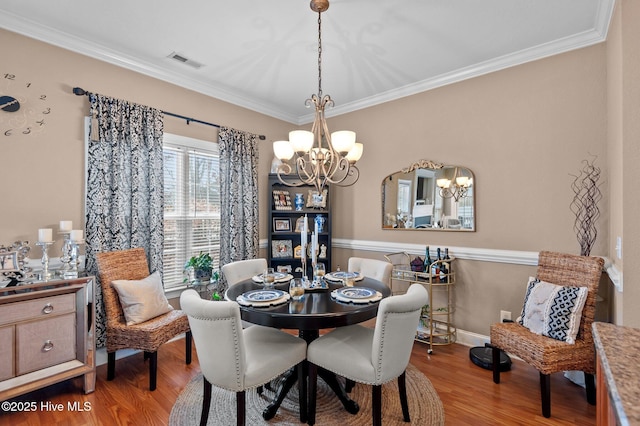 dining area with ornamental molding, wood-type flooring, and a notable chandelier