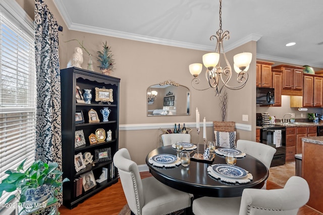 dining room featuring sink, wood-type flooring, a notable chandelier, and ornamental molding