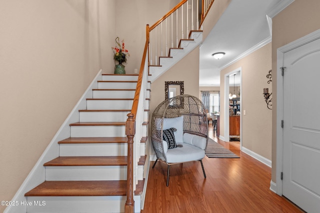 staircase with hardwood / wood-style flooring, a notable chandelier, and crown molding