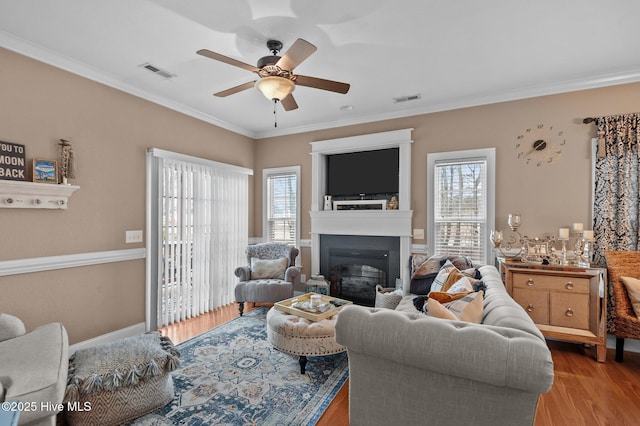 living room featuring ceiling fan, ornamental molding, and light wood-type flooring