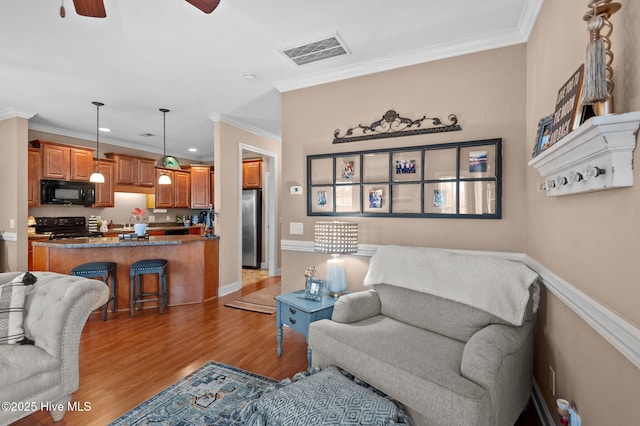 living room featuring ceiling fan, light wood-type flooring, and crown molding