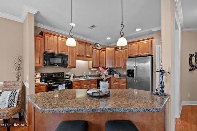 kitchen with a kitchen breakfast bar, hanging light fixtures, ornamental molding, and black appliances