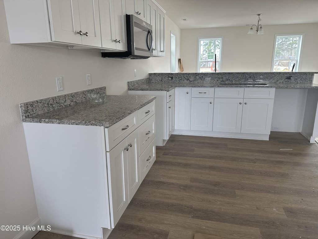 kitchen with dark hardwood / wood-style floors, kitchen peninsula, and white cabinets