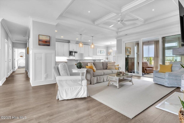 living room with light wood-type flooring, ornamental molding, coffered ceiling, ceiling fan, and beam ceiling