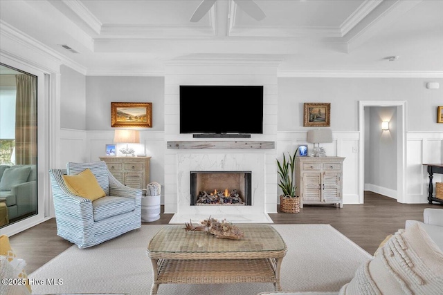 living room featuring ceiling fan, crown molding, a high end fireplace, and dark wood-type flooring