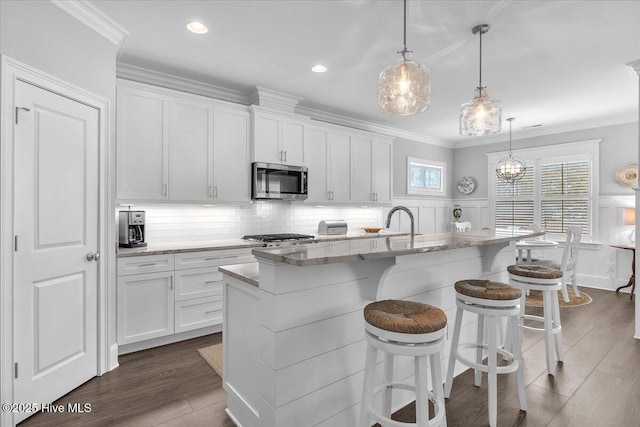 kitchen with decorative light fixtures, white cabinetry, and a kitchen island with sink