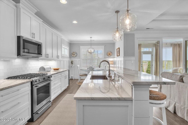 kitchen with a spacious island, sink, crown molding, decorative light fixtures, and stainless steel appliances