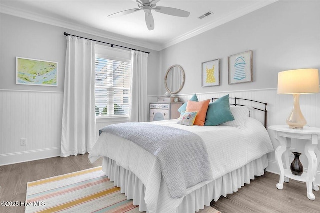 bedroom with wood-type flooring, ceiling fan, and ornamental molding