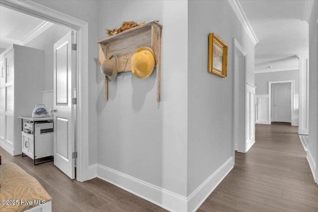 corridor featuring dark hardwood / wood-style floors, ornamental molding, and decorative columns