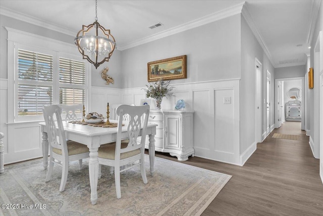 dining room with hardwood / wood-style floors, ornamental molding, and an inviting chandelier