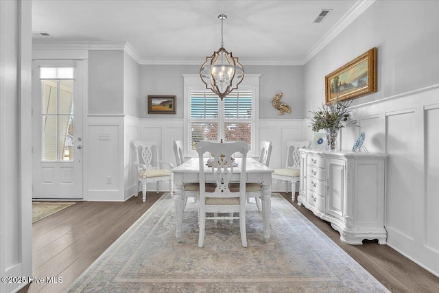 dining room with dark hardwood / wood-style floors, an inviting chandelier, and crown molding