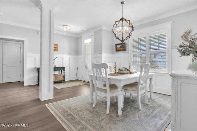 dining area featuring a chandelier, ornamental molding, ornate columns, and dark wood-type flooring