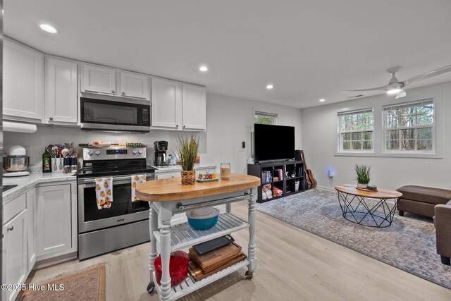 kitchen with white cabinets, light wood-type flooring, stainless steel appliances, and sink