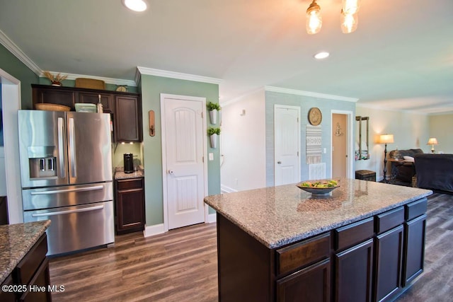 kitchen with light stone countertops, stainless steel fridge, dark brown cabinetry, dark wood-type flooring, and a center island