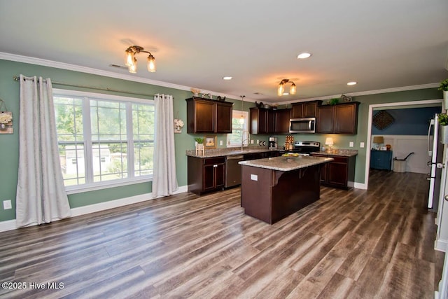 kitchen featuring appliances with stainless steel finishes, a kitchen breakfast bar, dark brown cabinetry, a kitchen island, and hanging light fixtures