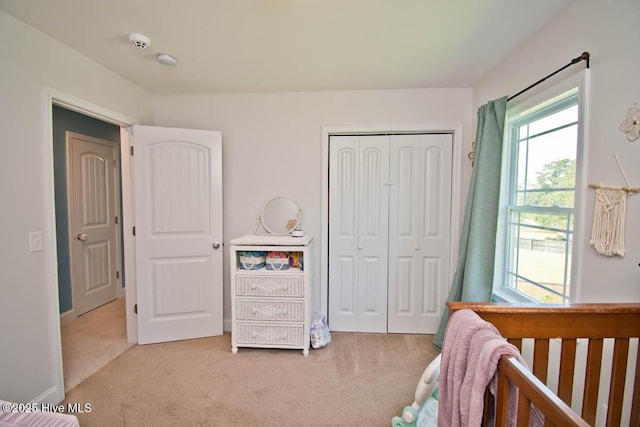 bedroom featuring a closet, light colored carpet, and a nursery area