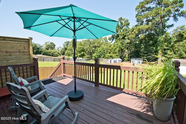 wooden terrace with a storage unit and a lawn